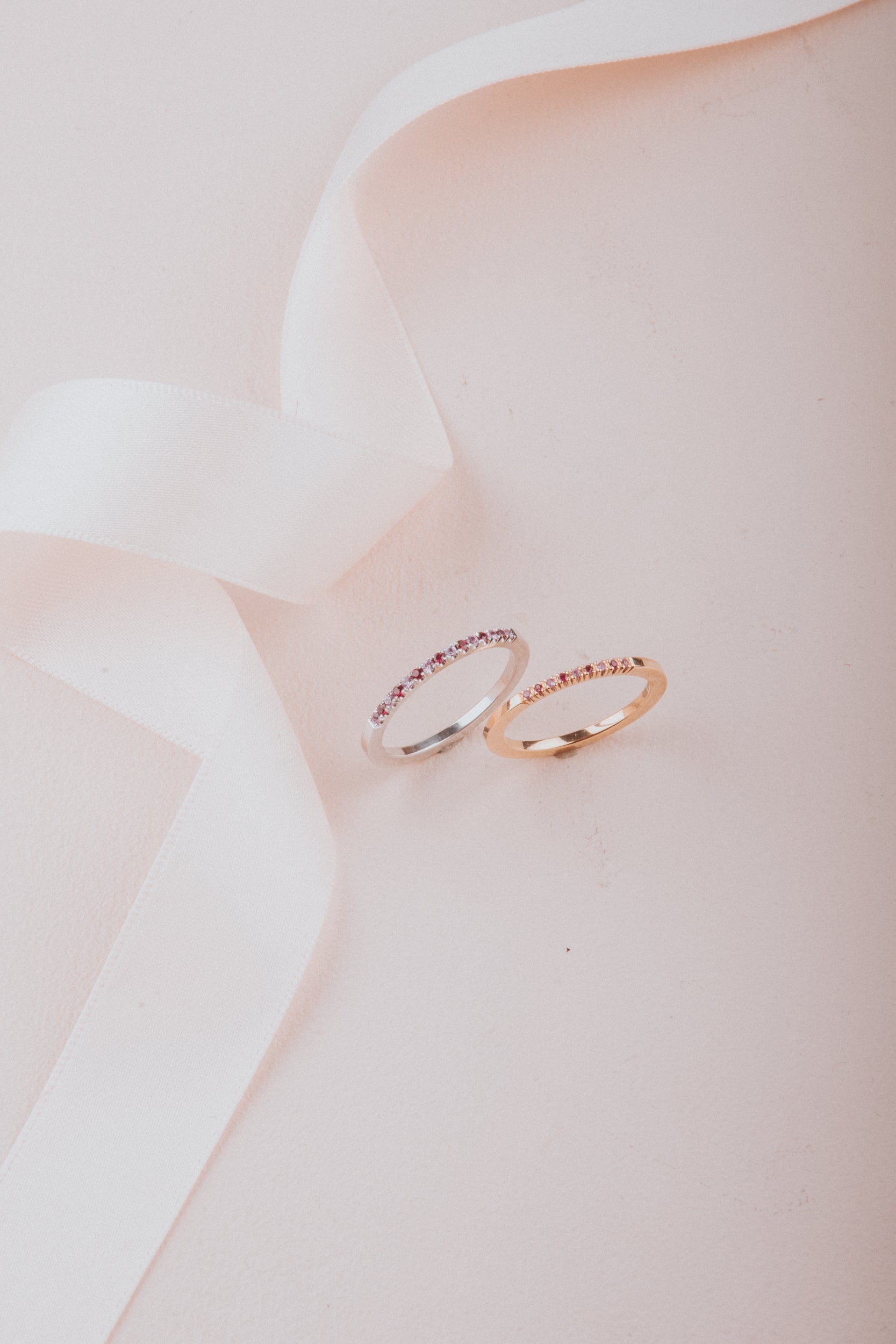Två eleganta ringar med rosa stenar på ljus bakgrund.