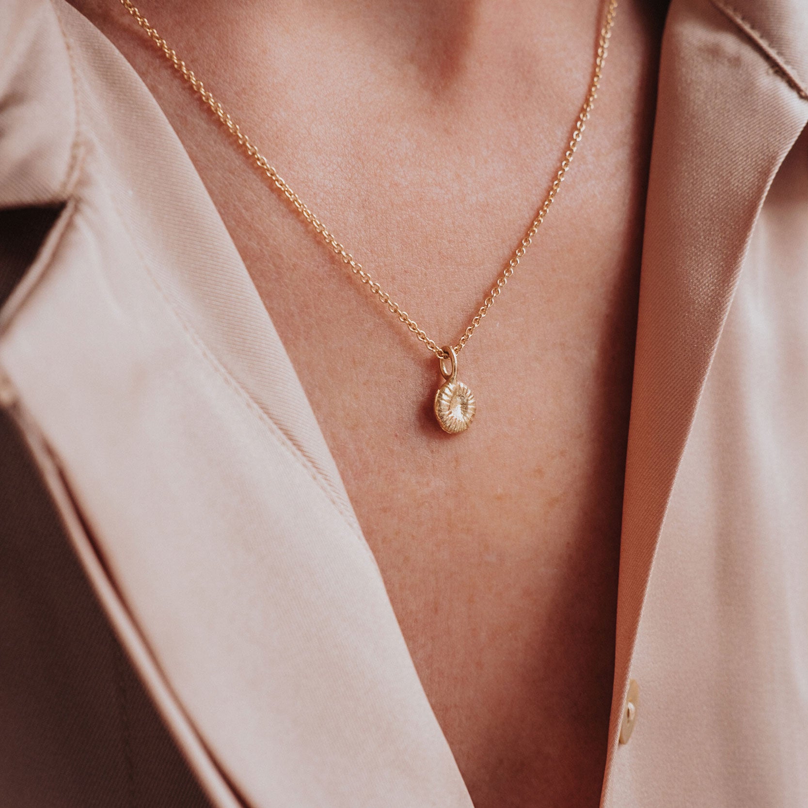 Närbild på knappkorallberlock i guld