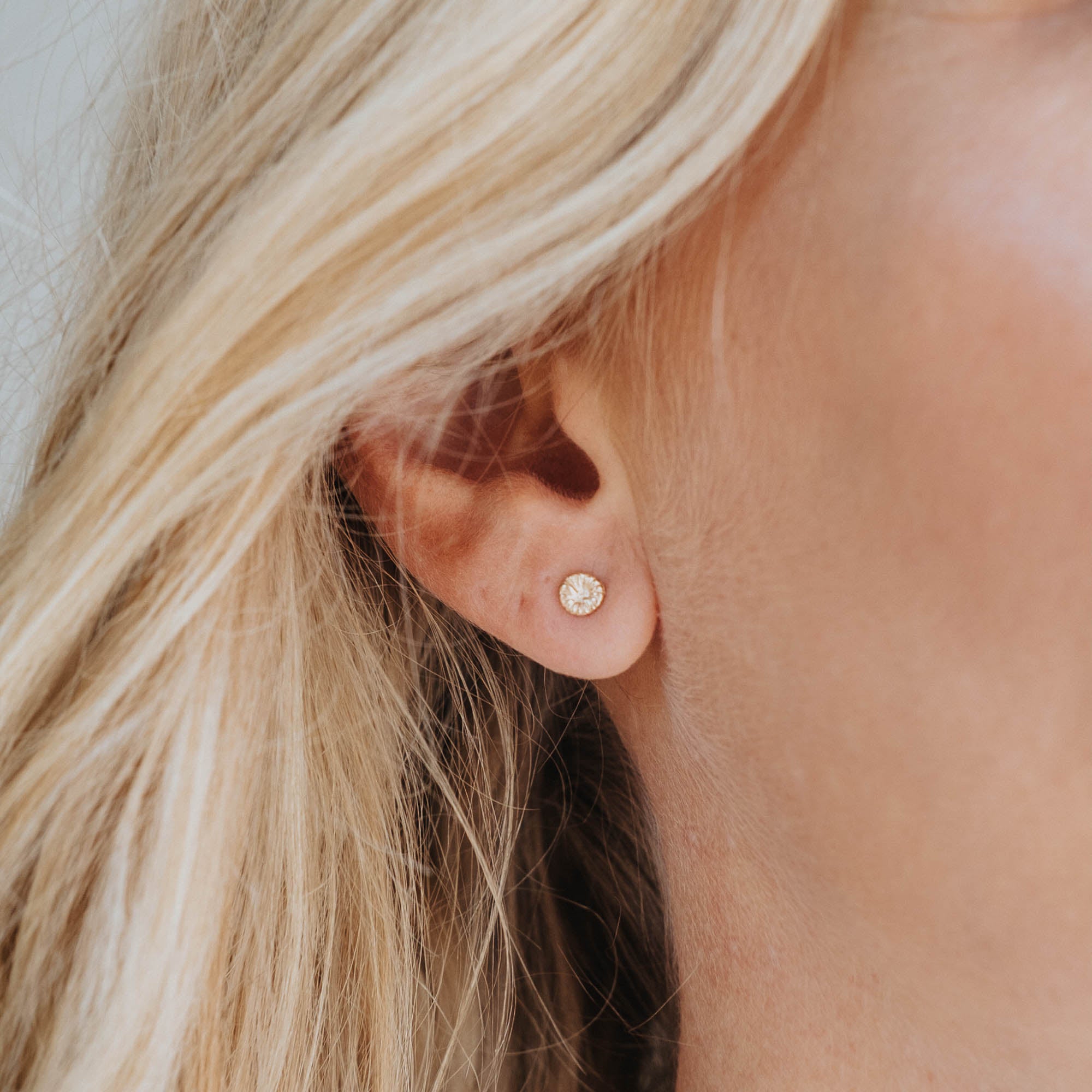 Knappkorall örhänge i guld på öra