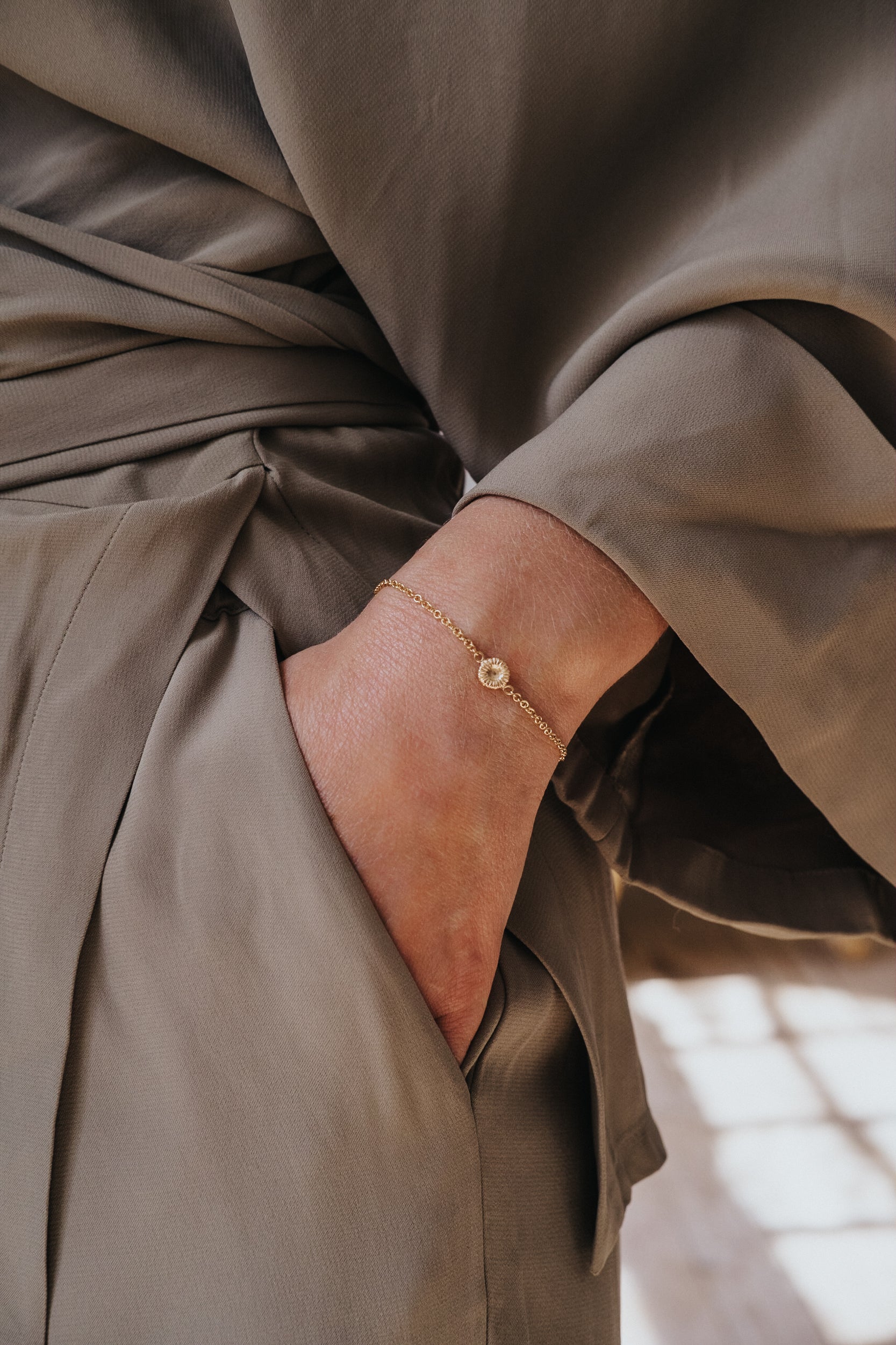 Guldarmband med knappkorall på hand